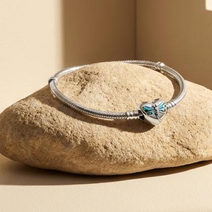 Bracciale elegante con pietre scintillanti e dettagli raffinati, posato su una pietra liscia vicino a una finestra luminosa, ideale per accessori di moda e gioielli di lusso.